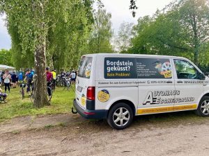 VW Transporter auf MSR Verpflegungsstation mit pausierenden Radlern im Hintergrund